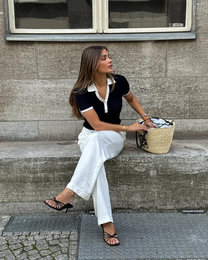 Mediterranean summer outfit with navy and white collared top, white wide-leg trousers, black minimal sandals and natural straw tote bag