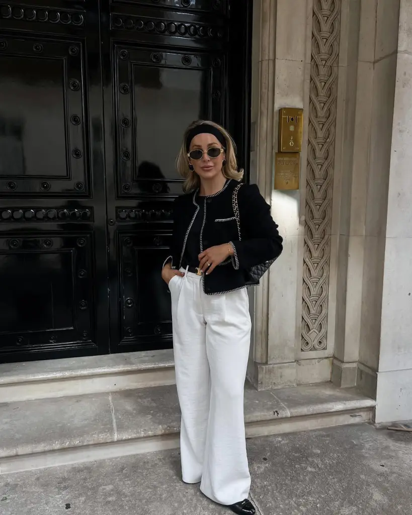 Luxury designer outfit with black boucle jacket with white trim, white wide-leg trousers, black headband, small round sunglasses and quilted chain shoulder bag