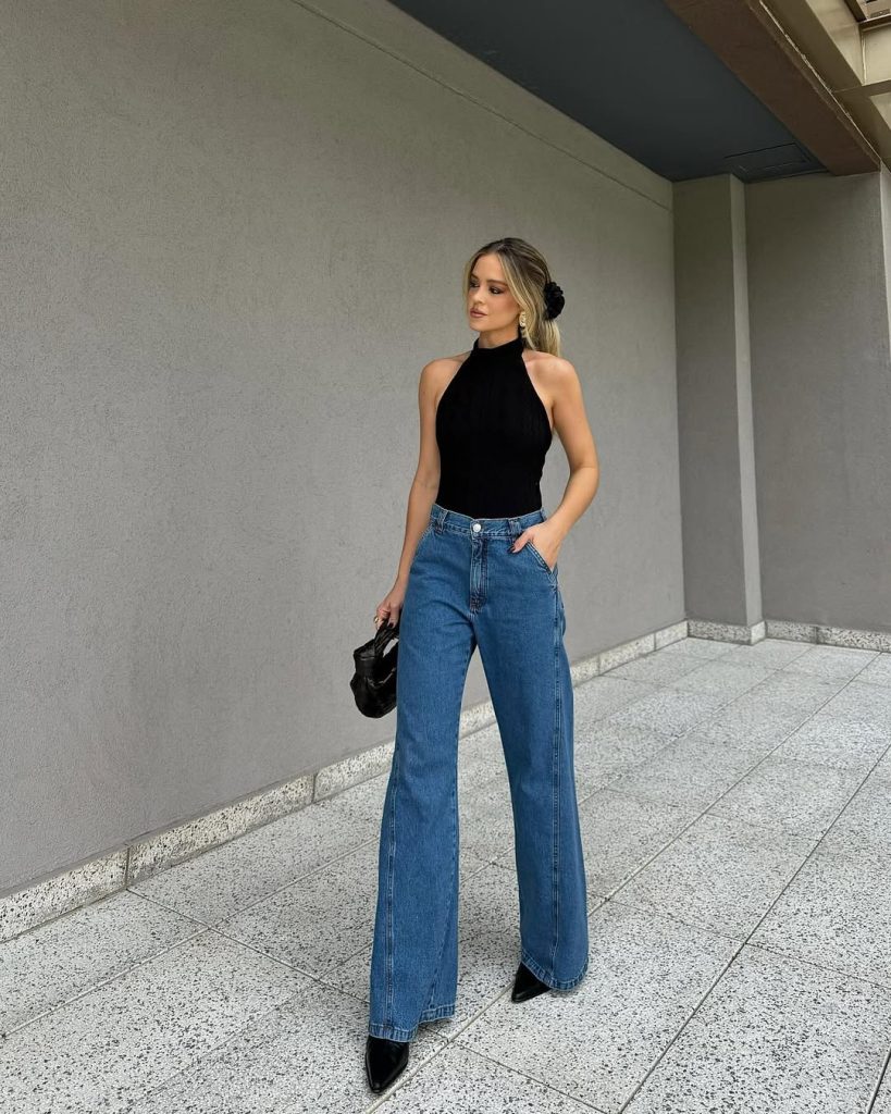 Woman in black halter top and wide leg jeans with black heels

