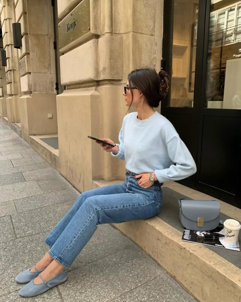 Casual spring outfit with powder blue sweater, straight leg jeans, blue mary jane flats and grey structured bag
