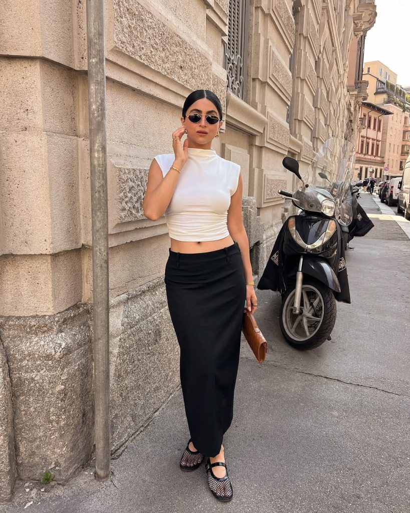 Woman in white crop top and black maxi skirt with woven flats
