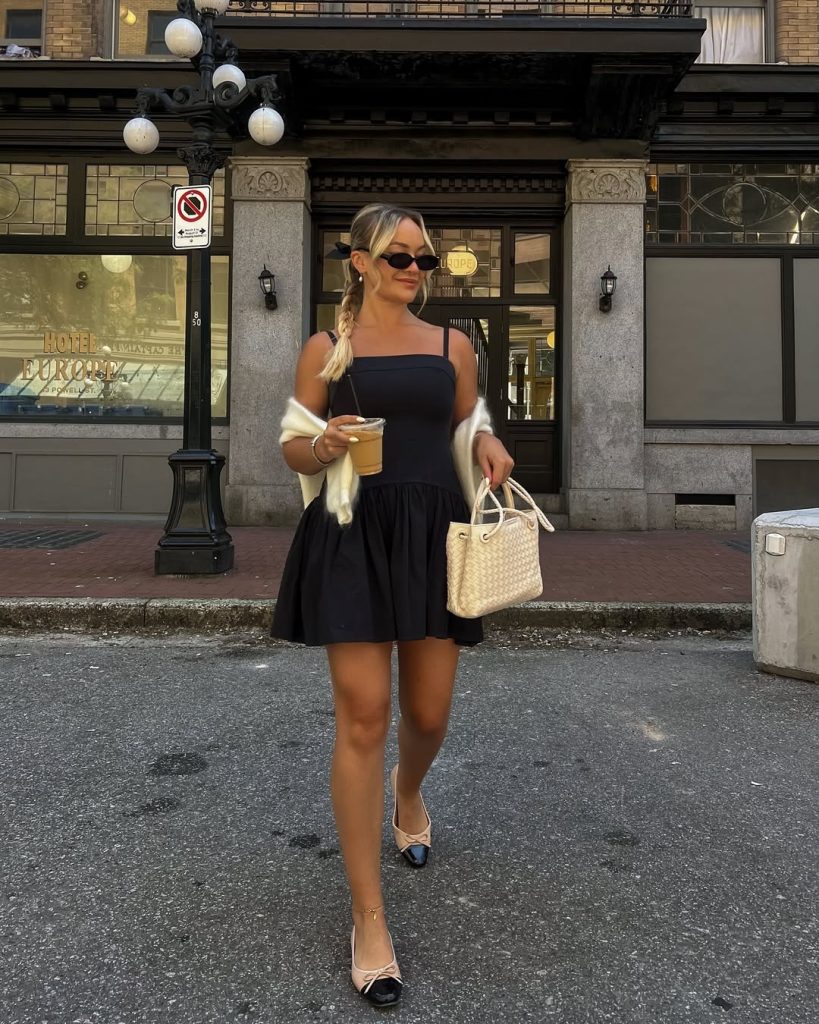 Woman in black mini dress and cream cardigan with two-tone flats
