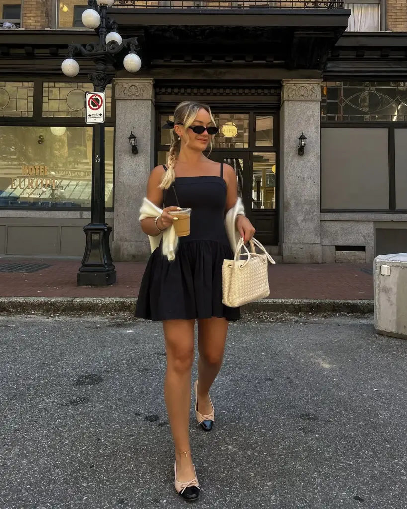 Woman in black mini dress and cream cardigan with two-tone flats
