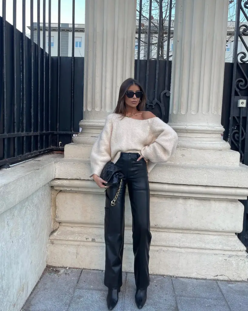 Woman wearing off shoulder cream sweater with black leather pants and boots