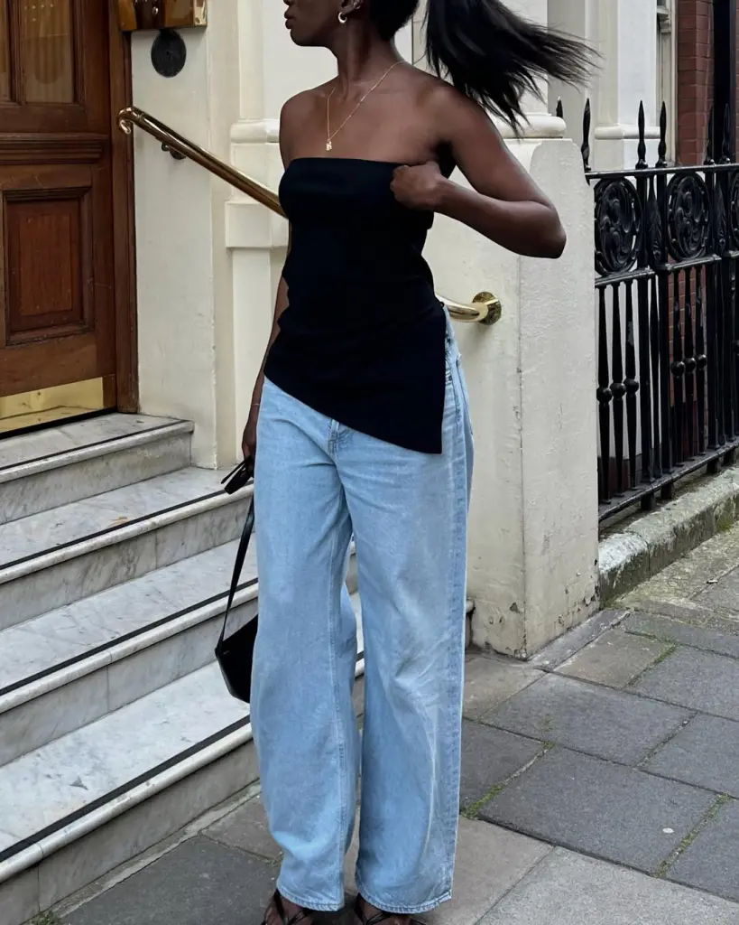 Woman wearing black asymmetric tube top and light wash wide leg jeans