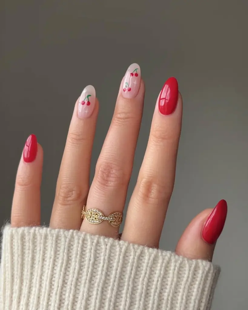 Cherry nail art with glossy red polish and nude pink base