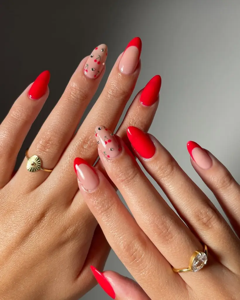 Almond shaped red nails with cherry accents and rhinestones