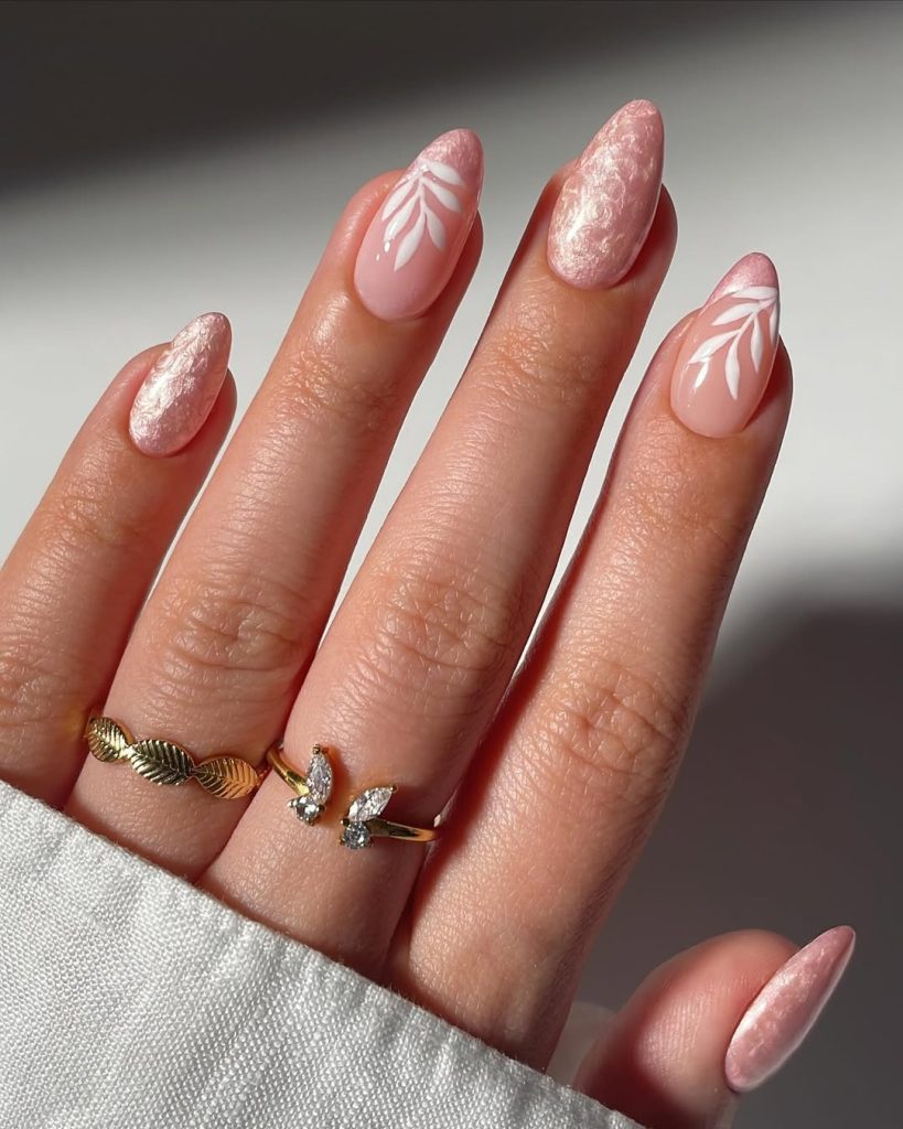 shimmery pink almond nails with white floral patterns