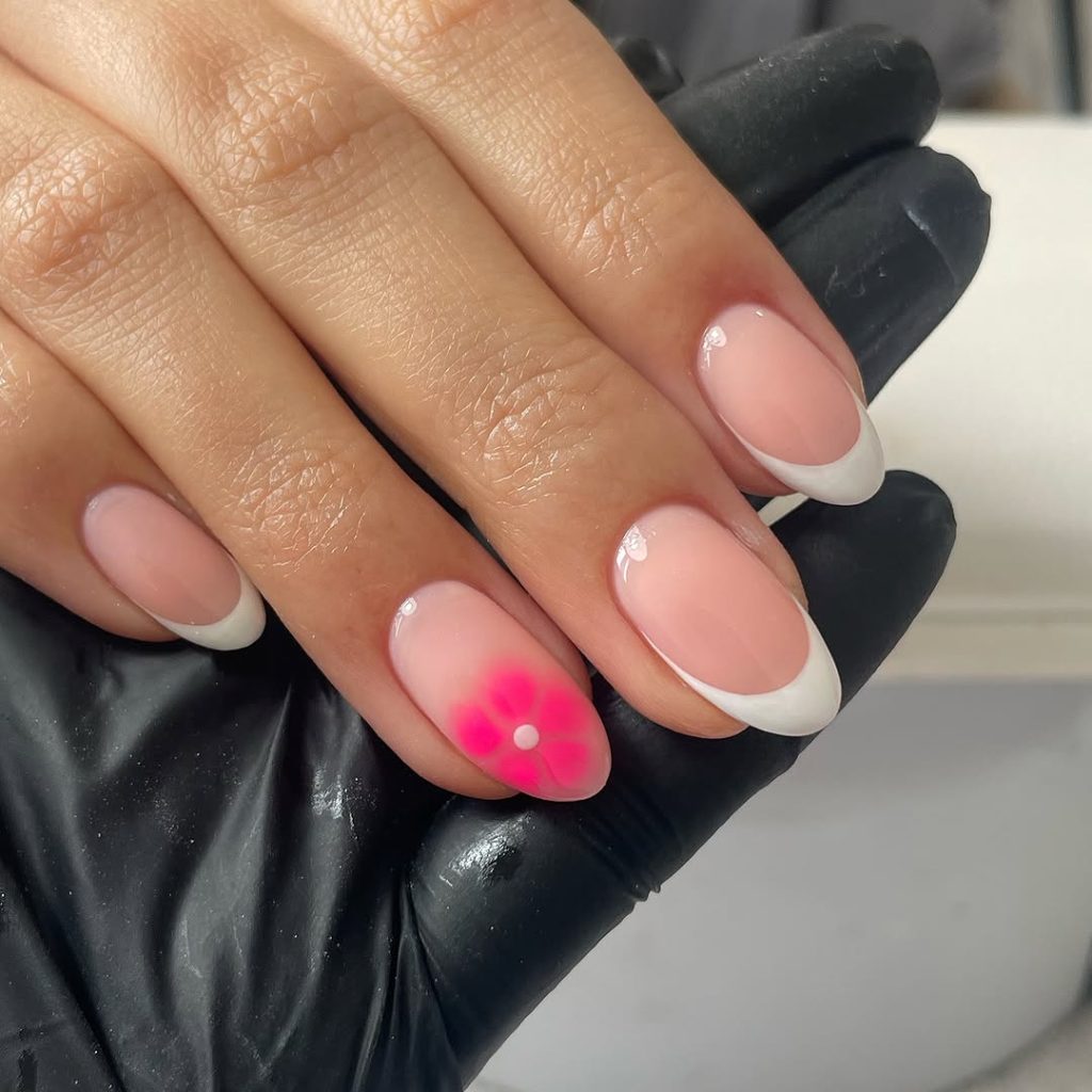 Neutral pink nails with white French tips and hot pink flower accent