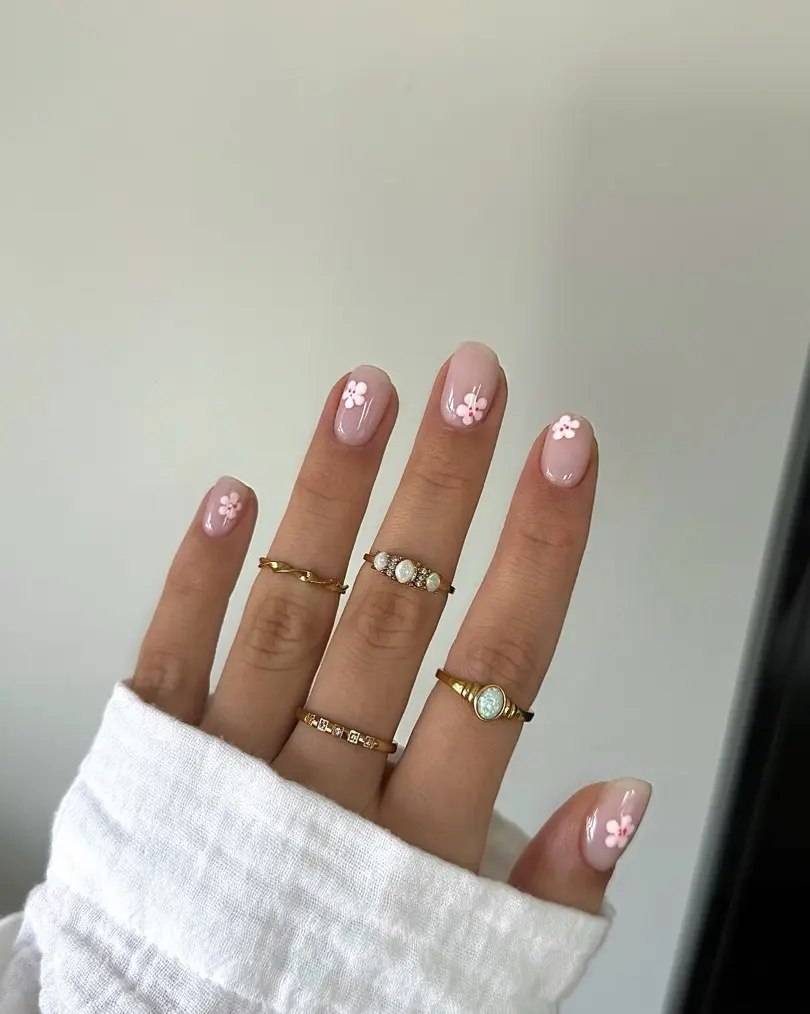 Short pink nails with white flower details and gold rings