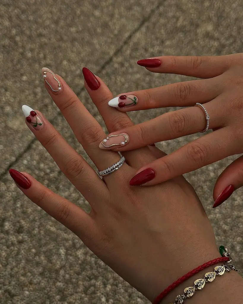 Wine red nails with metallic accents and cherry designs