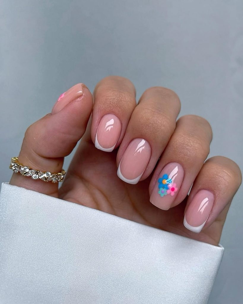 Short French tips with blue flower accent
