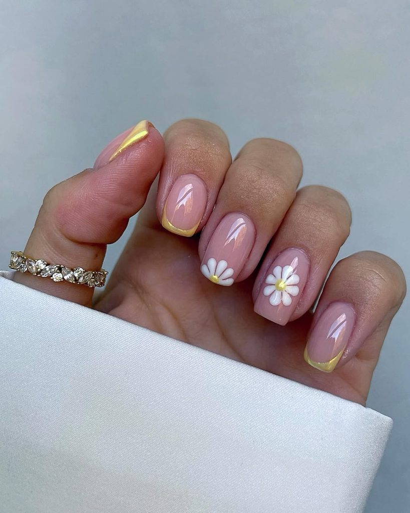 Short nude nails with yellow tips and white daisy details
