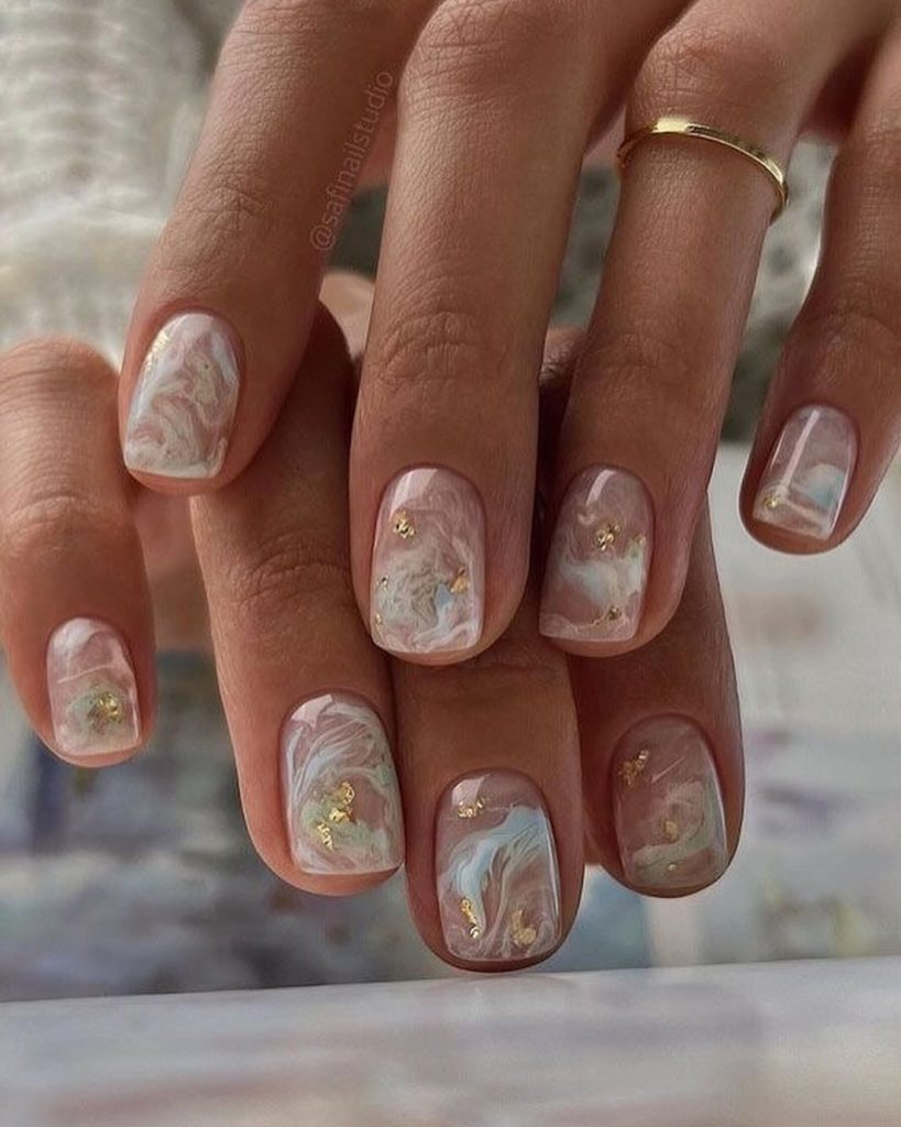 Short marble nails with gold flakes and pastel swirls
