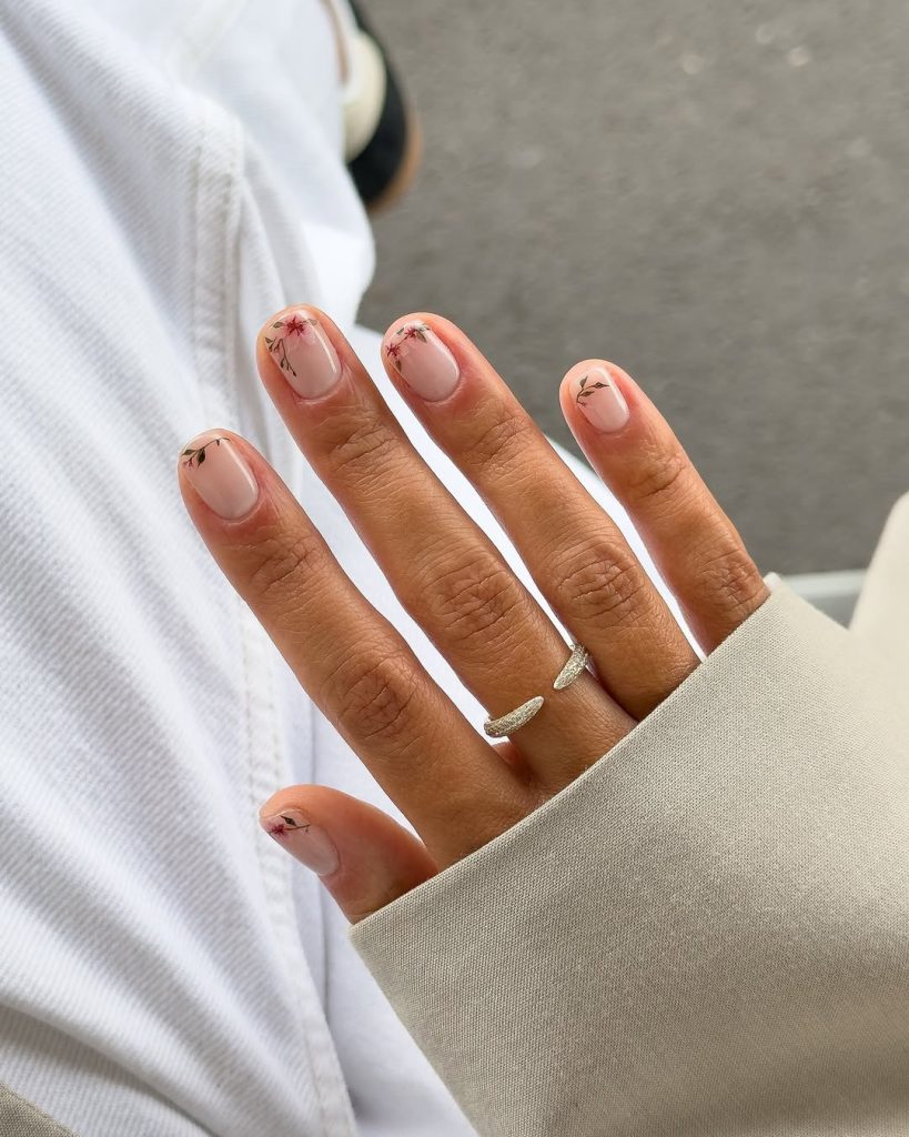 Short nude nails with red flower corner designs
