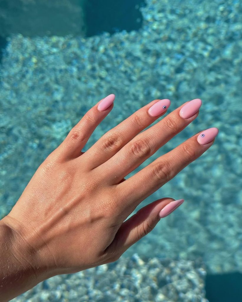 Soft pink almond nails with micro evil eye details
