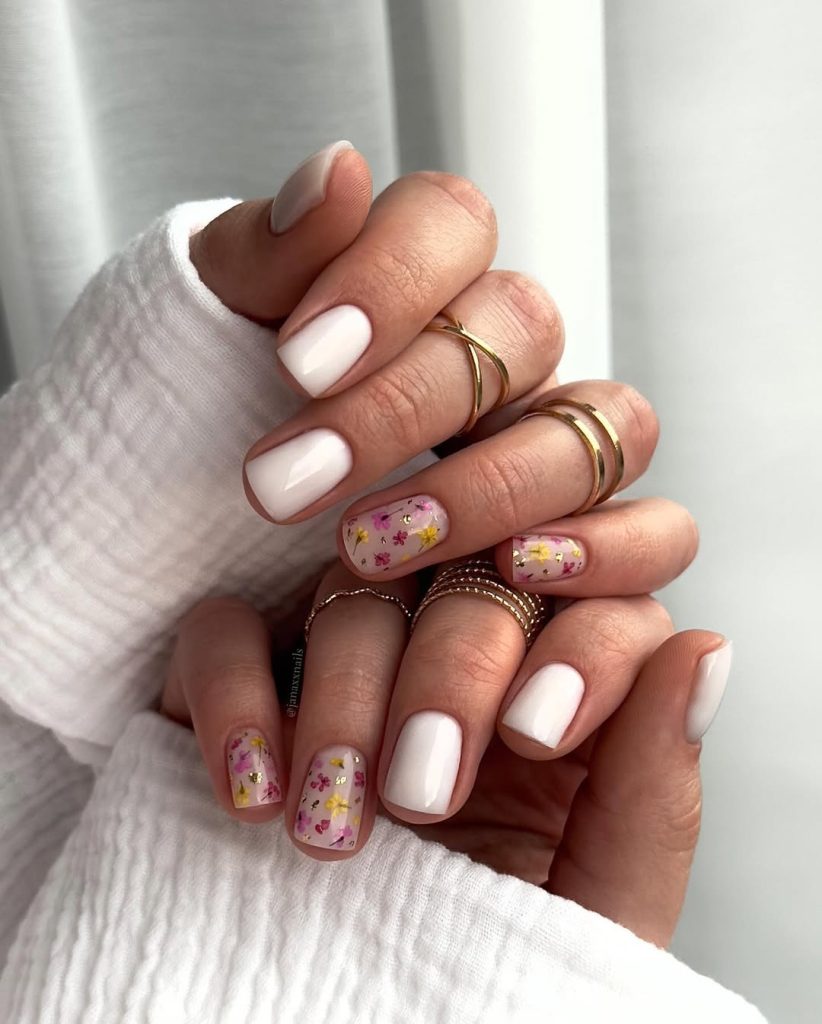Short milky white nails with pressed flowers on accent nail
