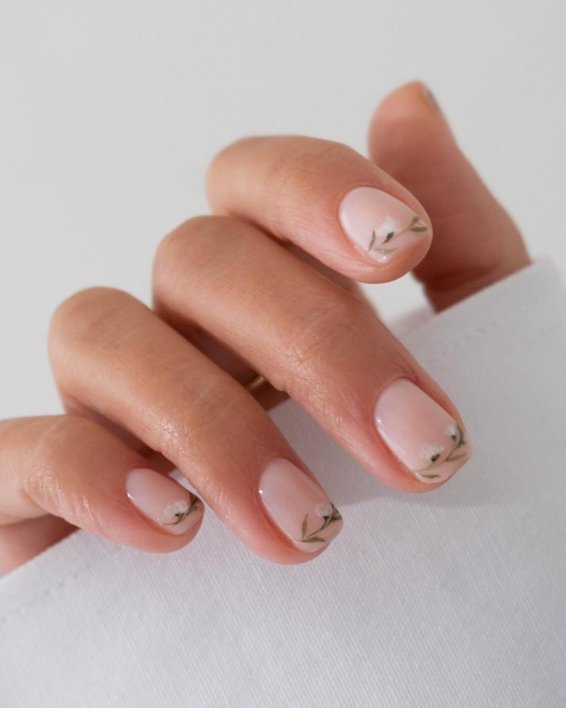 Short nude nails with minimal green leaf details
