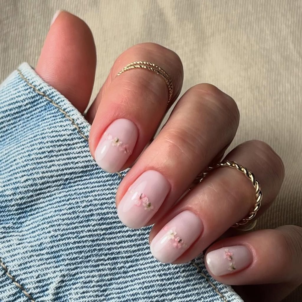 Short milky pink nails with tiny flower accents
