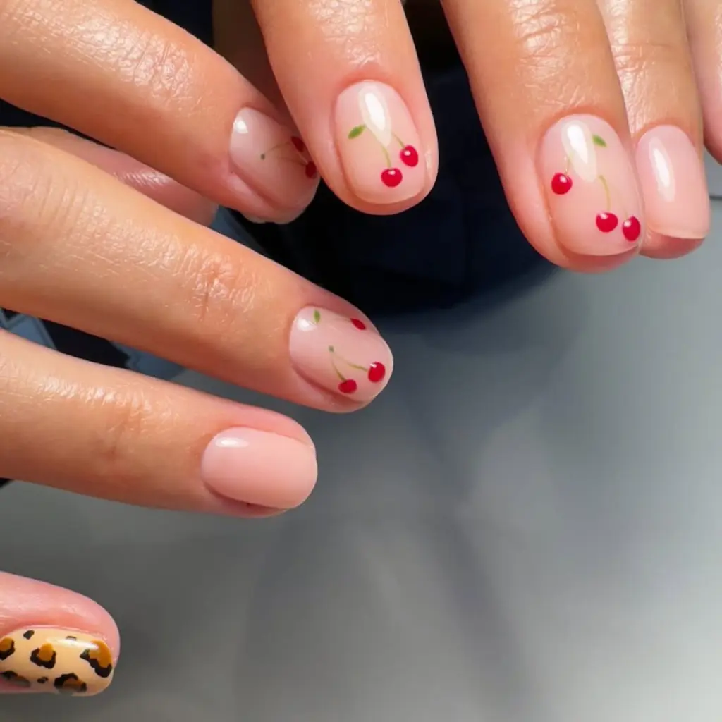 Short round nails with cherry details and leopard accent