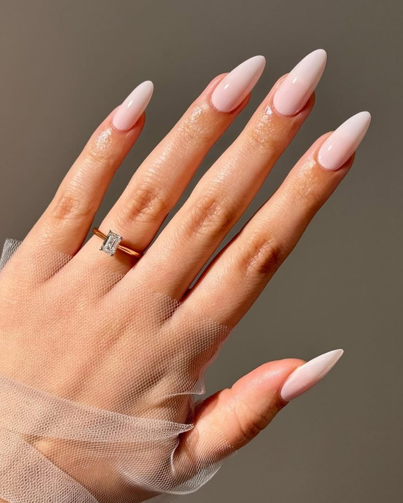 Milky pink polish on long almond nails