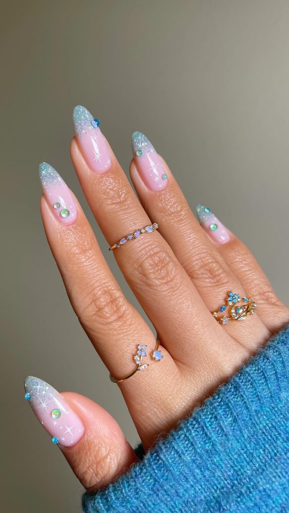 Pink almond nails with iridescent blue glitter tips, crystals and star details
