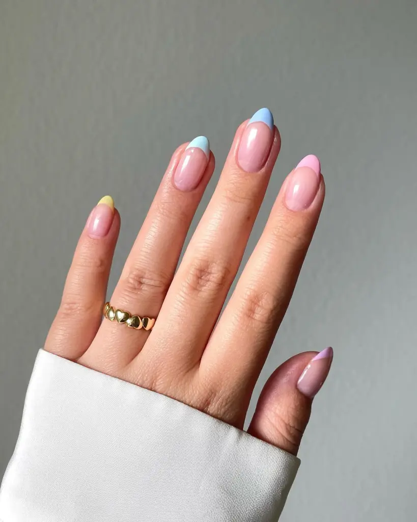 Elegant almond-shaped nails with glossy nude base and colorful pastel French tips in yellow, blue, pink, and lavender, perfect for spring elegance.
