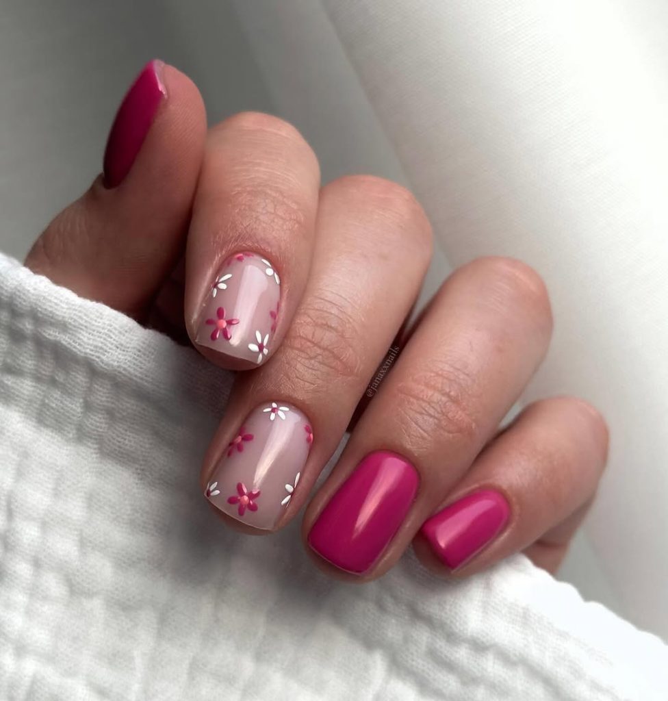Short square nails with fuchsia pink polish on two nails and sheer base with pink and white daisy flowers on remaining nails