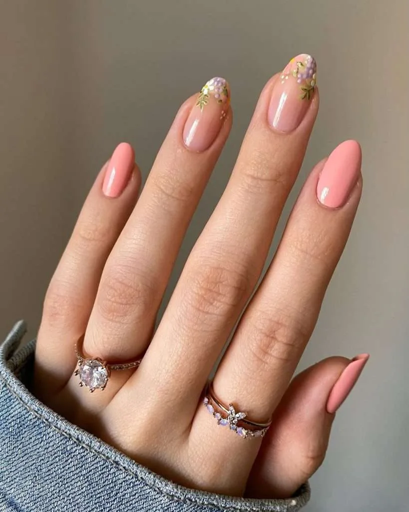 Medium almond nails with pink base, peach accent nails and detailed floral tip design in lavender and green