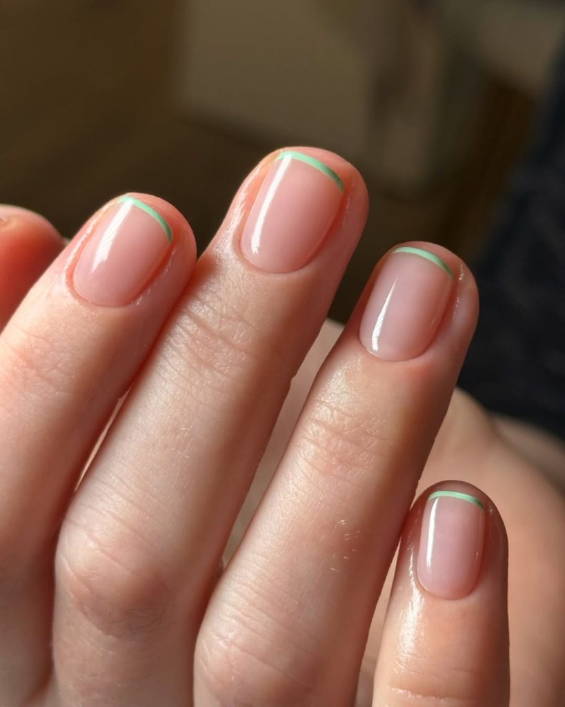 Short square nails with glossy nude pink base featuring subtle mint green micro-French tips

