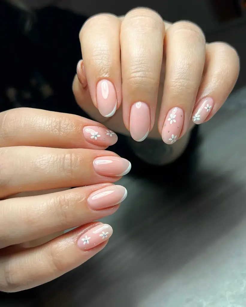 Almond shaped pink nails with white French tips and small white daisy flower accents
