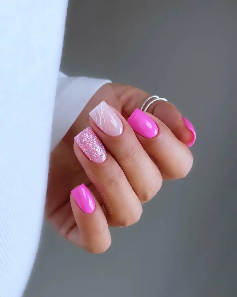 Short square nails with mix of hot pink polish, pink glitter nail, and milky pink base with white swirl design