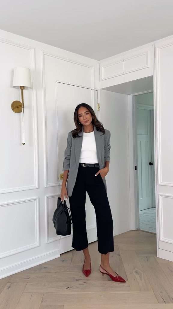 Business casual outfit with grey blazer, white top, black cropped trousers, thin belt, red pointed slingback heels and black structured handbag