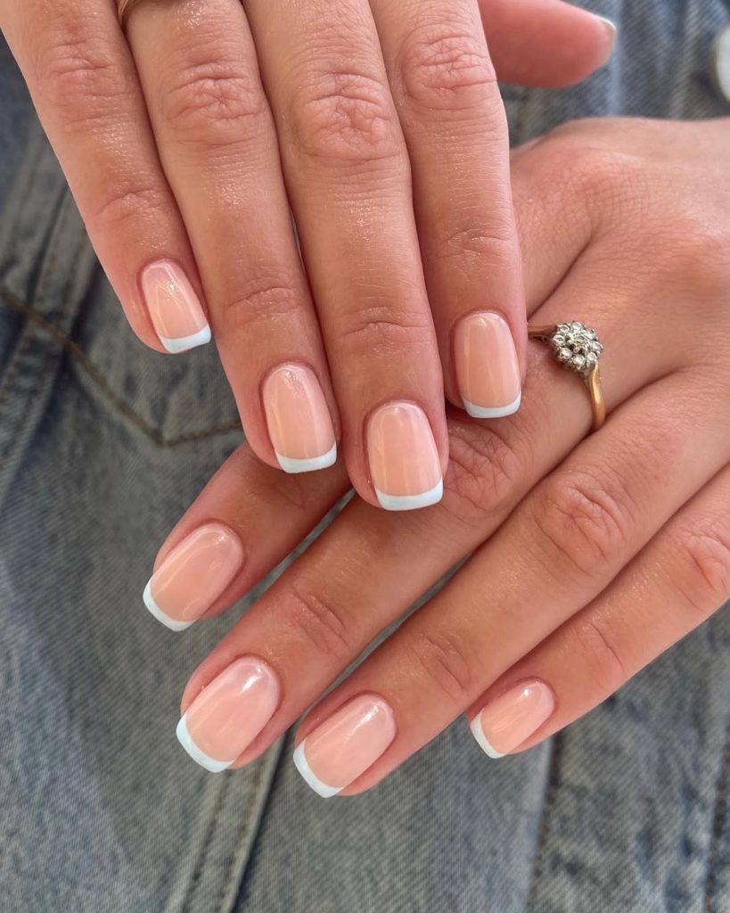 Short square nails with sheer nude base and baby blue French tips, creating a fresh spring twist on the classic French manicure
