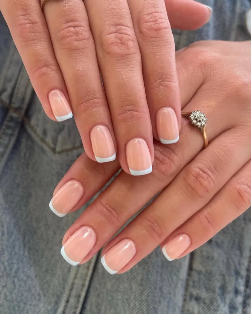 Short square nails with sheer nude base and baby blue French tips, creating a fresh spring twist on the classic French manicure
