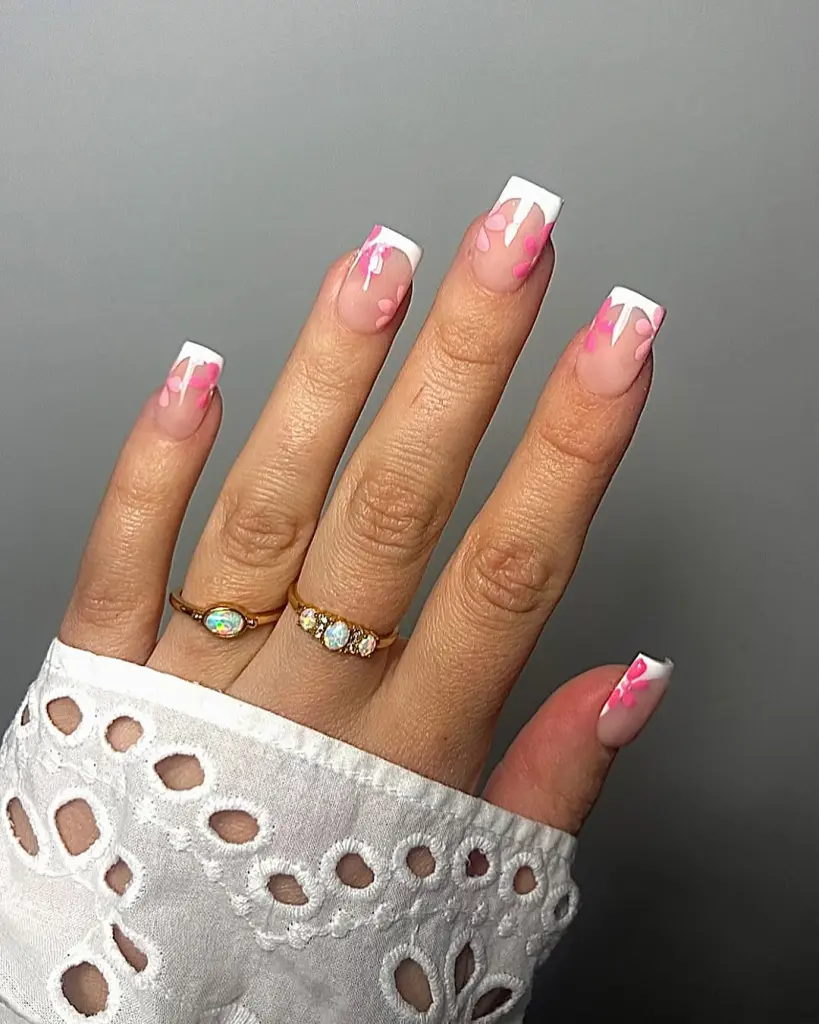 Square nails with transparent pink base, white French tips and pink flower petals
