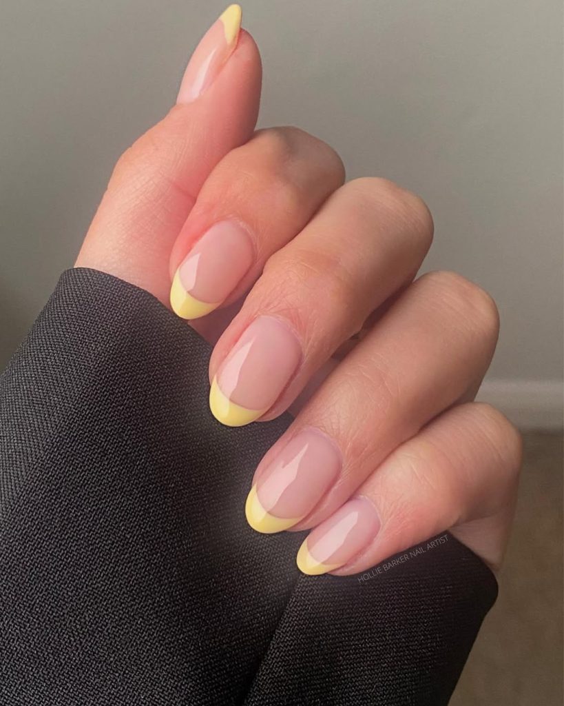 Oval-shaped sheer nude nails with vibrant pastel yellow French tips
