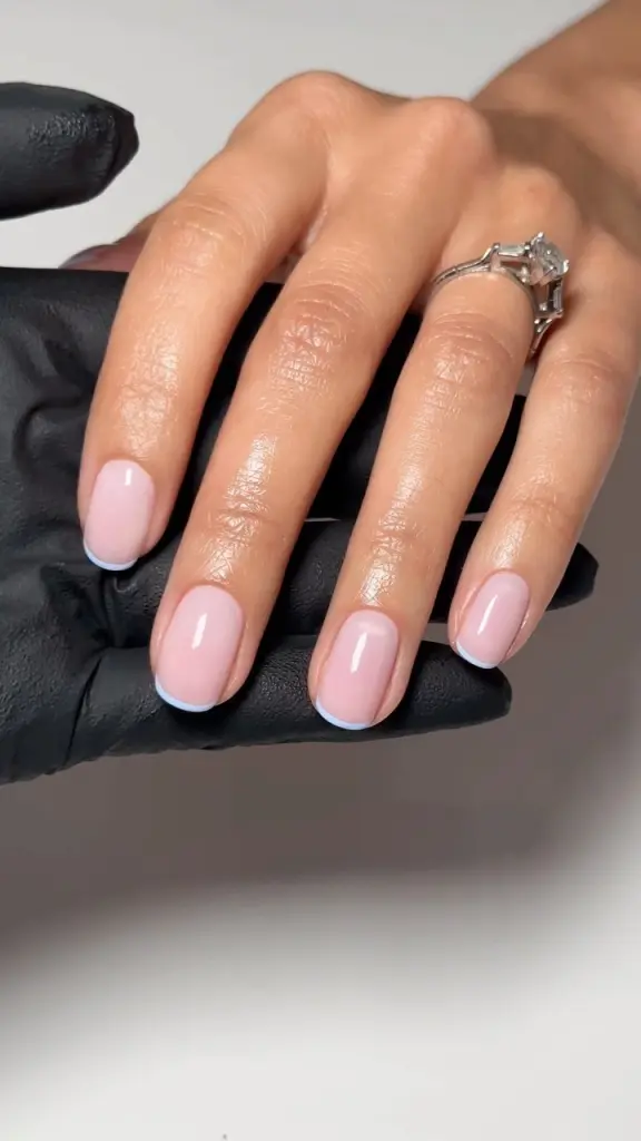 Oval-shaped nails with pink base and light blue French tips creating a fresh spring look
