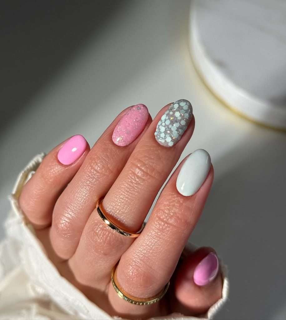 Short oval nails with pink, sparkly pink, blue hex glitter and white polish mix
