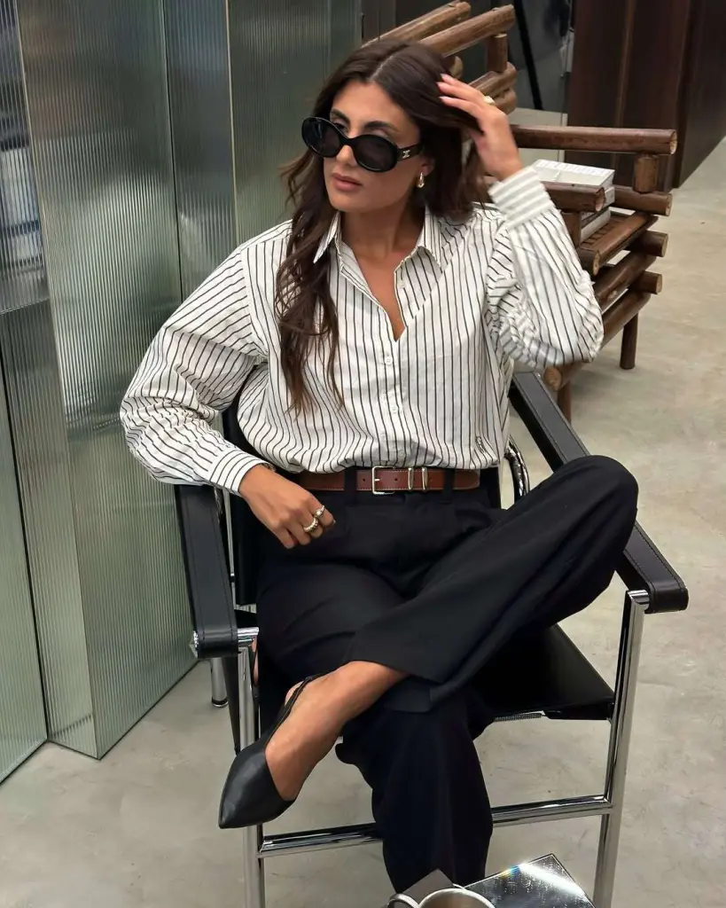 Business casual outfit with white and black striped oversized shirt, black wide-leg trousers, brown leather belt and black pointed flats