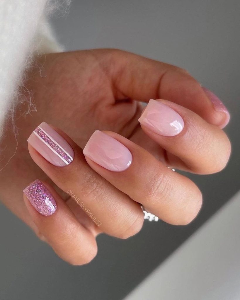 Short square nails with milky pink polish, pink glitter accent nail, and thin pink glitter stripe detail on one nail
