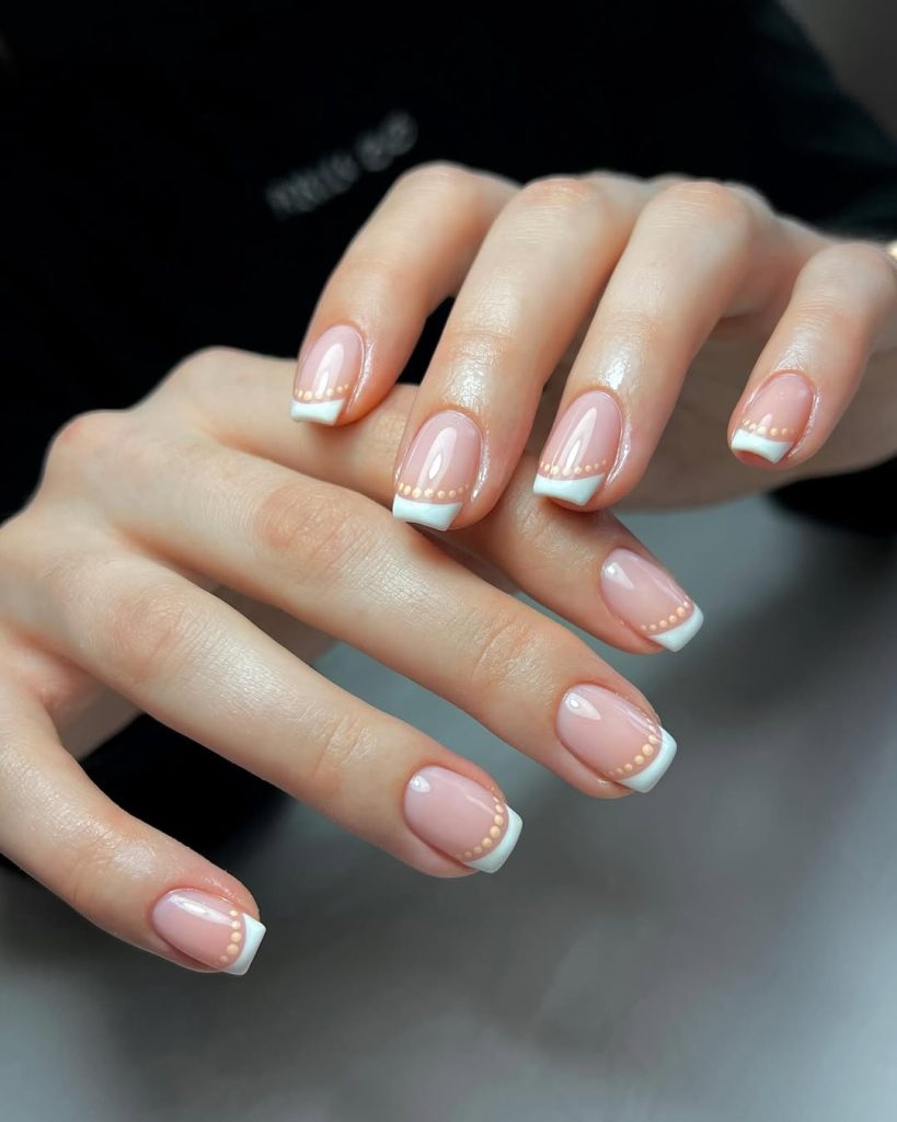 Square nails with pink base, classic white French tips and delicate peach dot accents
