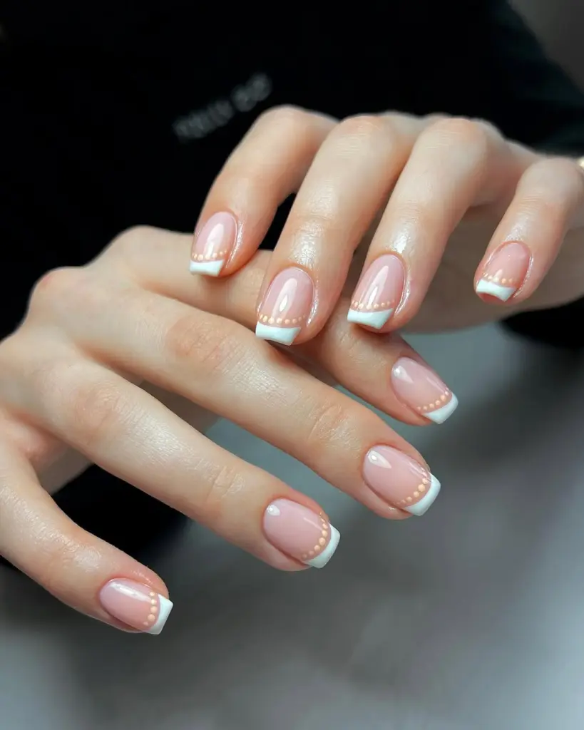 Square nails with pink base, classic white French tips and delicate peach dot accents
