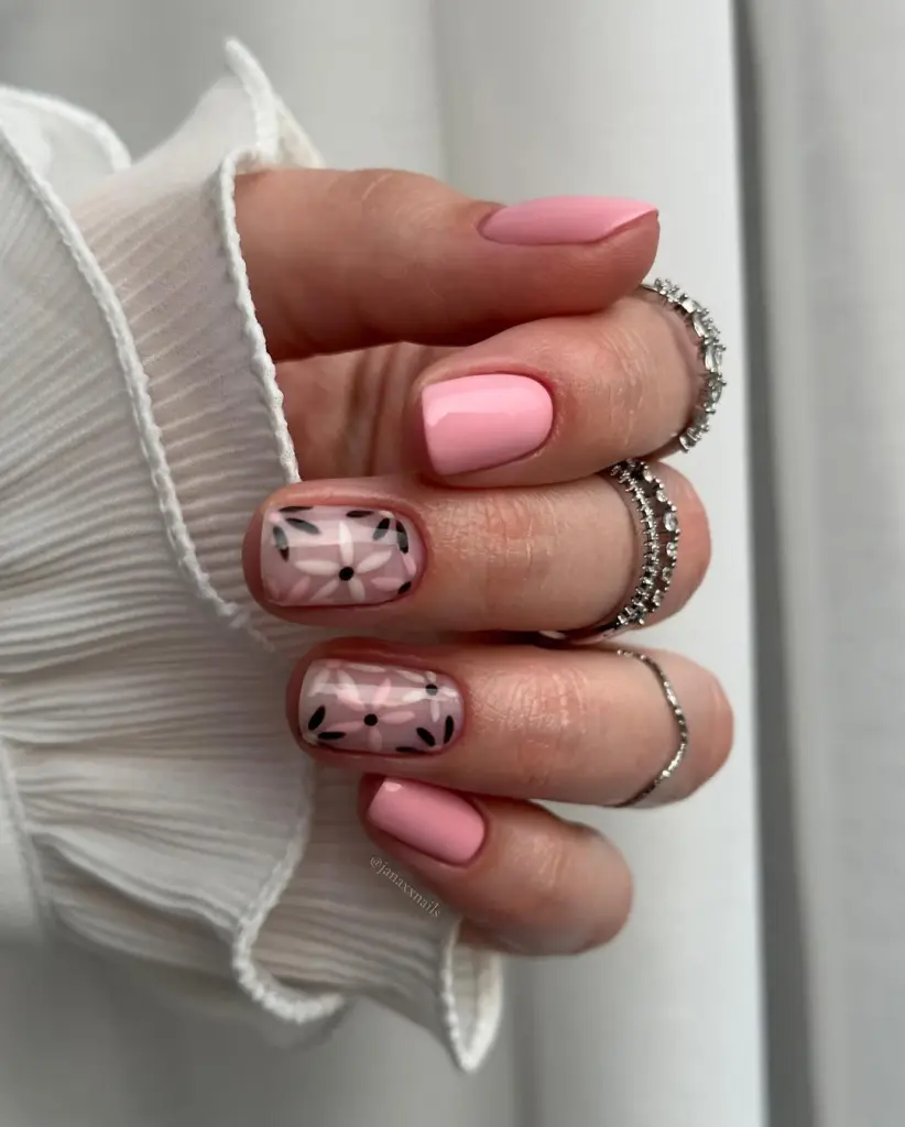 Short square nails with pink color and transparent pink accent nails with baby pink flowers and black leaf details
