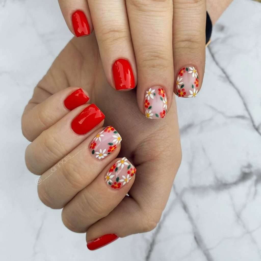 Short square nails with bright red polish and pink base accent nails with white daisy and red flower floral design
