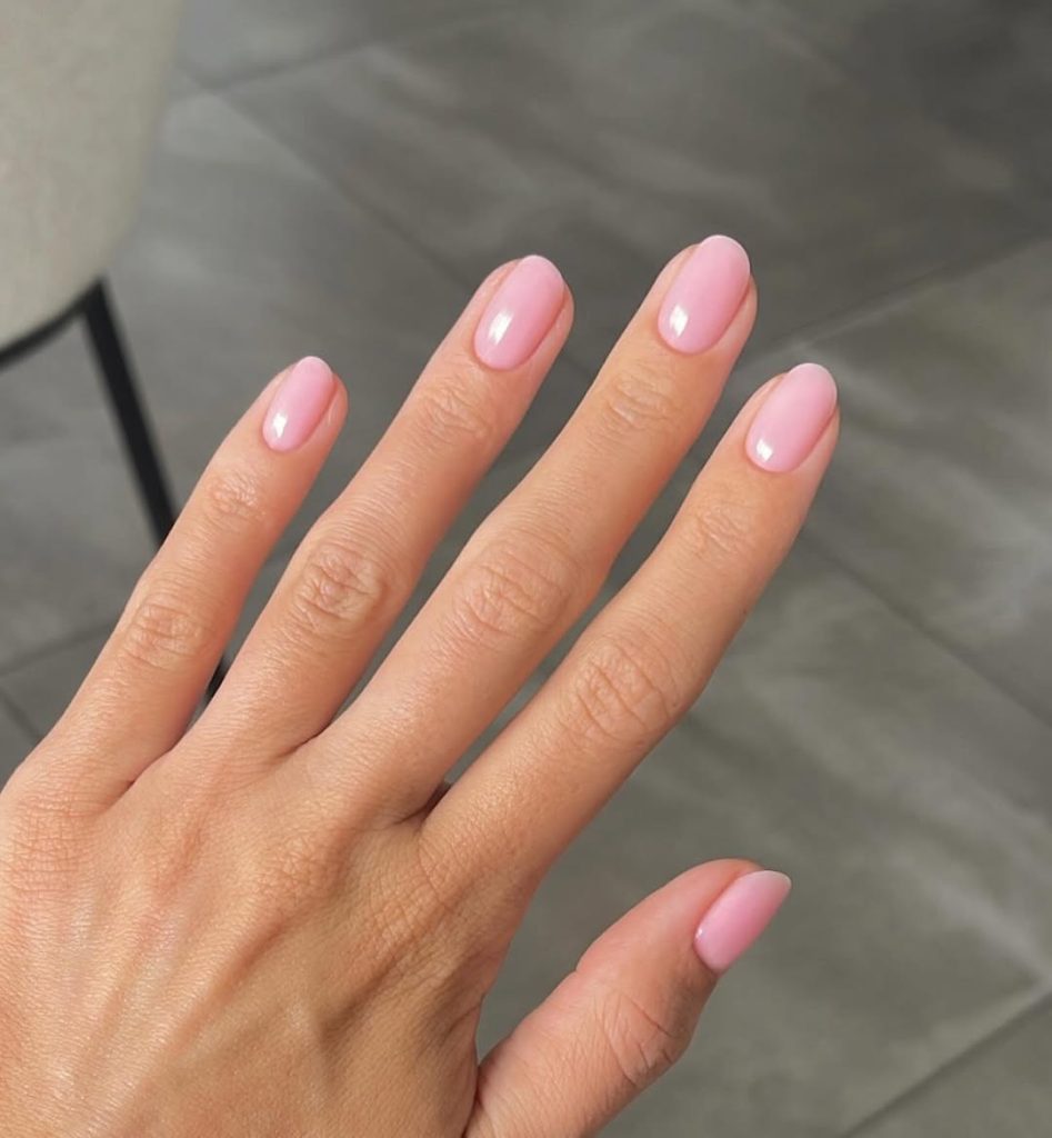 Short oval nails with translucent milky pink polish and high-shine finish

