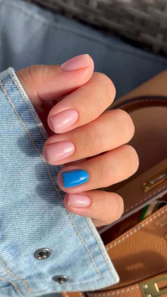 Short square nails with soft pink polish and one bright blue accent nail