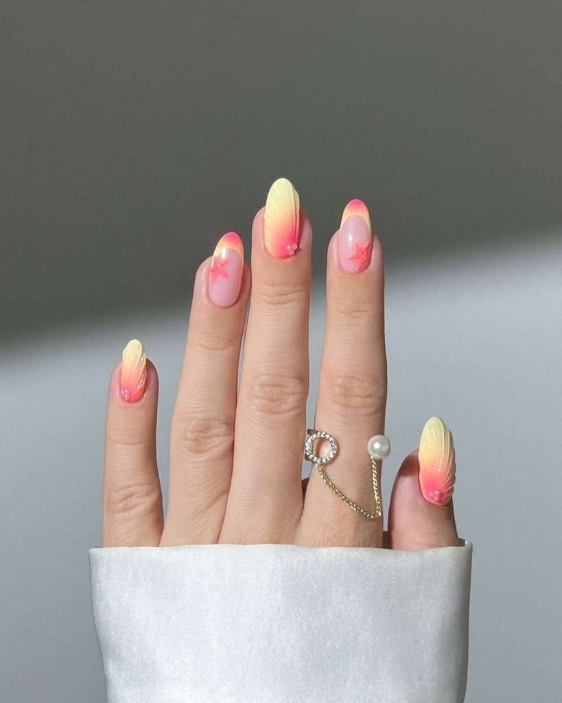 Long almond nails with pink base, coral and yellow gradient French tips, and pink starfish designs
