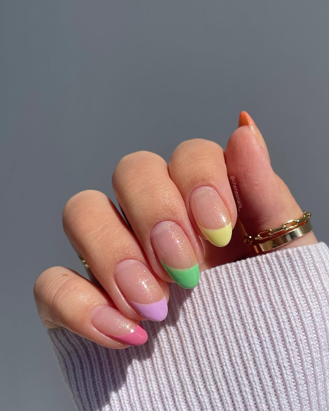 Almond-shaped nails with shimmery nude base and multicolored French tips in pastel pink, lavender, mint green, and yellow creating a playful spring color palette
