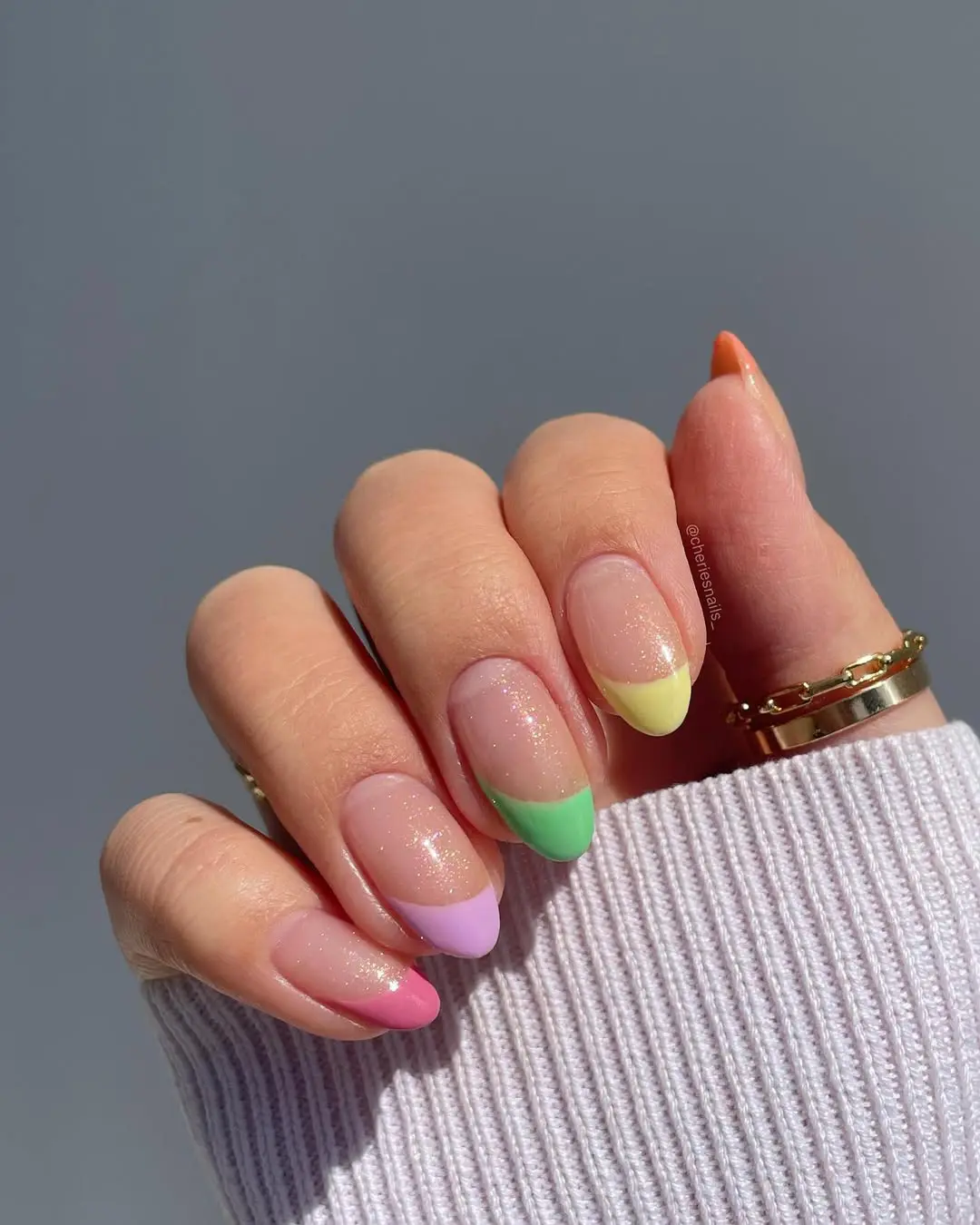 Almond-shaped nails with shimmery nude base and multicolored French tips in pastel pink, lavender, mint green, and yellow creating a playful spring color palette
